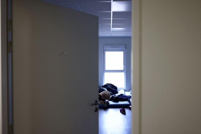 A person lays in a bed at an empty school near the Blandan's park in Lyon, south-eastern France, on January 10, 2026 where homeless families are being housed by a collective. Classrooms turned into dormitories and a cafeteria: more than 80 children without a roof over their heads are occupying an empty school in Lyon with their parents, in an operation of a "highly exceptional" scale carried out on January 9, 2026 evening by the collective "Jamais Sans Toit" (JST) due to the lack of housing solutions. (Photo by Alex MARTIN / AFP)