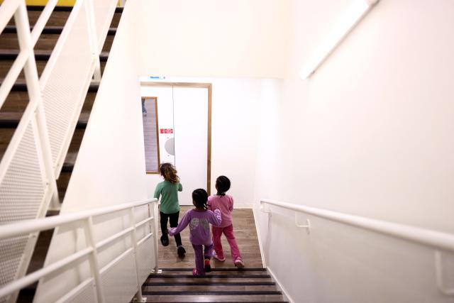 Children play in a corridor at an empty school near the Blandan's park in Lyon, south-eastern France, on January 10, 2026 where homeless families are being housed by a collective. Classrooms turned into dormitories and a cafeteria: more than 80 children without a roof over their heads are occupying an empty school in Lyon with their parents, in an operation of a "highly exceptional" scale carried out on January 9, 2026 evening by the collective "Jamais Sans Toit" (JST) due to the lack of housing solutions. (Photo by Alex MARTIN / AFP)