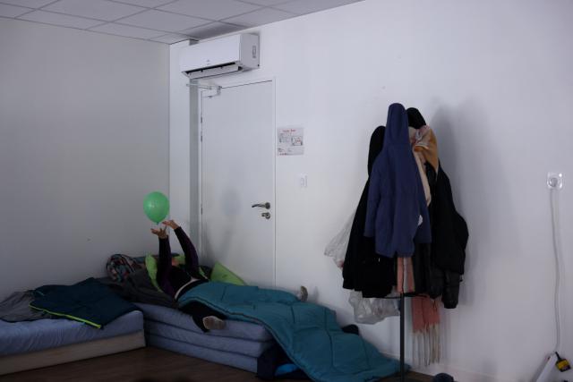A child plays in a bed at an empty school near the Blandan's park in Lyon, south-eastern France, on January 10, 2026 where homeless families are being housed by a collective. Classrooms turned into dormitories and a cafeteria: more than 80 children without a roof over their heads are occupying an empty school in Lyon with their parents, in an operation of a "highly exceptional" scale carried out on January 9, 2026 evening by the collective "Jamais Sans Toit" (JST) due to the lack of housing solutions. (Photo by Alex MARTIN / AFP)