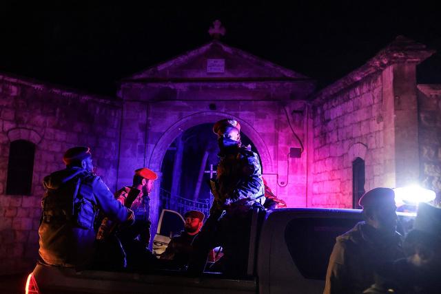 Government Syrian security forces sit in the back of a pick-up truck deployed outside a church following a ceasefire in the city of Aleppo, northern Syria early on January 11, 2026. The Kurdish-led Syrian Democratic Forces (SDF) said January 11, 2026, that they agreed under a ceasefire to withdraw their fighters from the two districts they held in Aleppo after deadly clashes in the city. "We reached an understanding that led to a ceasefire and secured the evacuation of the martyrs, the wounded, the trapped civilians and the fighters from Ashrafiyeh and Sheikh Maqsud neighbourhoods to northern and eastern Syria," the SDF wrote in a statement. Syria's official SANA news agency reported that "buses carrying the last batch of members of the SDF organisation have left the Sheikh Maqsud neighbourhood in Aleppo, heading towards northeastern Syria." (Photo by Bakr ALkasem / AFP)