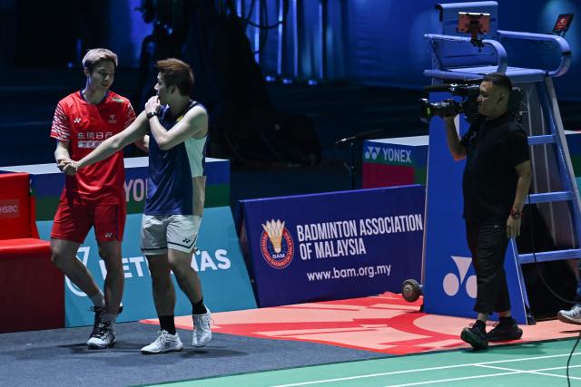 China's Shi Yuqi (L) walks with Thailand’s Kunlavut Vitidsarn (C) after he retired due to an injury during the men’s singles final against at the Malaysia Open badminton tournament in Kuala Lumpur on January 11, 2026. (Photo by MOHD RASFAN / AFP)