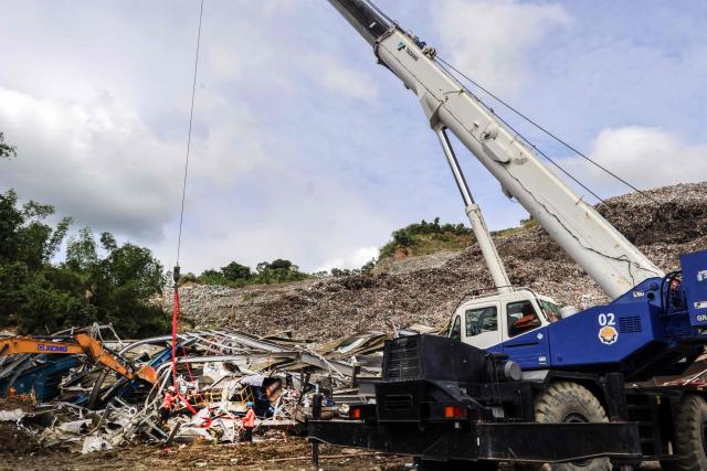 Staff use a crane to pull out large pieces of debris after a landslide at the landfill in Barangay Binaliw, Cebu City on January 11, 2026. Hard hat-wearing rescue workers and backhoes dug through rubble in search of survivors on January 10 in the shadow of a mountain of garbage that buried dozens of landfill employees in the central Philippines, killing at least six. (Photo by Cheryl Baldicantos / AFP)