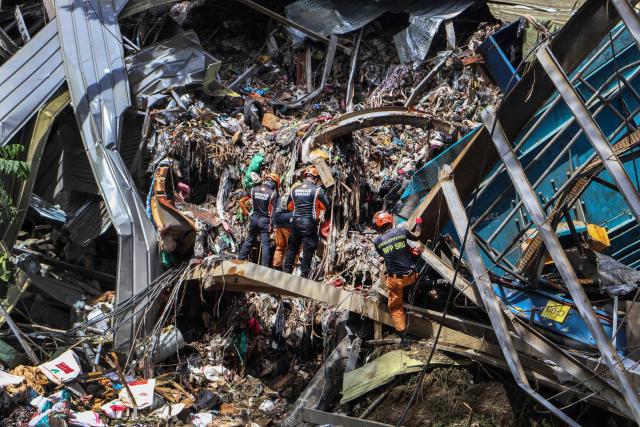 Members of the search and rescue team look for people after a landslide at the landfill in Barangay Binaliw, Cebu City on January 11, 2026. Hard hat-wearing rescue workers and backhoes dug through rubble in search of survivors on January 10 in the shadow of a mountain of garbage that buried dozens of landfill employees in the central Philippines, killing at least six. (Photo by Cheryl Baldicantos / AFP)