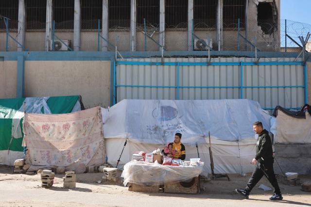 A displaced Palestinian man sits at his stall placed outside tent shelters set-up in the vicinity of The United Nations Relief and Works Agency for Palestine Refugees in the Near East's (UNRWA) headquarters, in Gaza City on January 11, 2026. The majority of Gaza's 2.4 million people have been displaced, often multiple times, by the war that began with Hamas's attack on southern Israel on October 7, 2023. With displaced families living in tented camps, a serious concerns has been raised over their living conditions. (Photo by Omar AL-QATTAA / AFP)