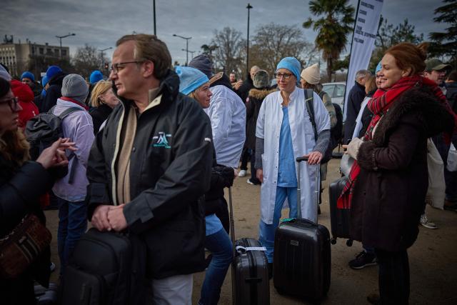 Thousands of medical professionals including, doctors, surgeons and anesthesistes queue to board buses as they leave France for Brussels during a mass exodus at Porte Dauphine in Paris on Janaury 11, 2026 as part of a strike from 5 till January 15 to denounce the nationals politics regarding their sector. (Photo by Kiran RIDLEY / AFP)