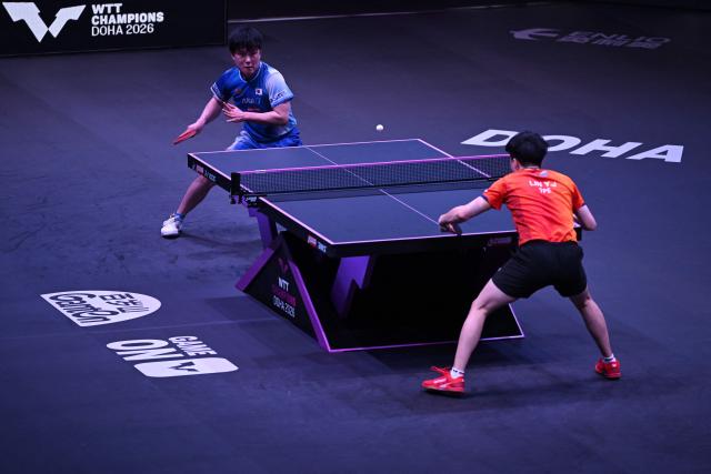 Japan's Tomokazu Harimoto (L) hits a return against Taiwan's Lin Yun-ju during their men's singles semi-final match during the World Table Tennis (WTT) Champions tournament at the Infinity Arena in Doha on January 11, 2026. (Photo by Mahmud HAMS / AFP)