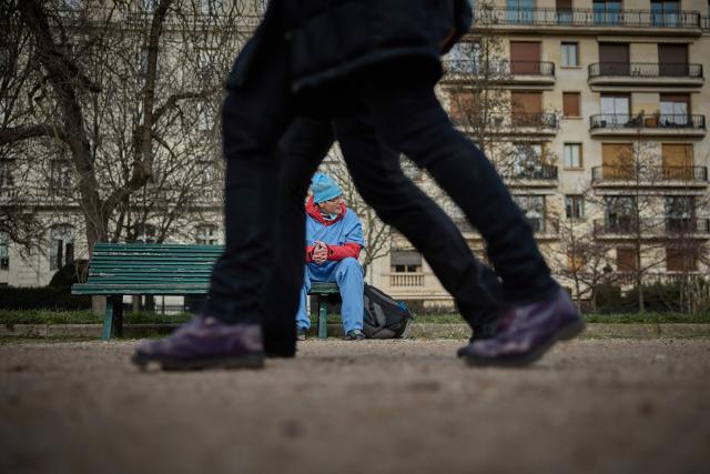 A medical staff sits on a bench as thousands of medical professionals including, doctors, surgeons and anaesthetists queue to board buses as they leave France for Brussels during a mass exodus at Porte Dauphine in Paris on January 11, 2026 as part of a strike from 5 till January 15 to denounce the nationals politics regarding their sector. (Photo by Kiran RIDLEY / AFP)