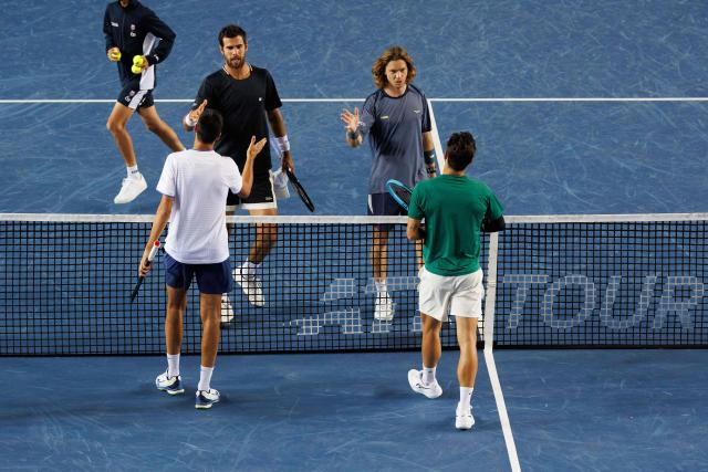 Italy's Lorenzo Sonego (L) and Lorenzo Musetti (R) shake hands with Russia's Andrey Rublev (2R) and Karen Khachanov after winning their men's doubles final match at the Hong Kong Tennis Open in Hong Kong on January 11, 2026. (Photo by May JAMES / AFP)
