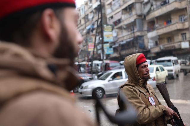 Syrian security officers patrol the streets following a ceasefire in the Kurdish-majority Ashrafiyeh neighbourhood of the city of Aleppo, northern Syria on January 11, 2026. Syria's Kurdish fighters said on January 11, 2026, that they agreed under a ceasefire to withdraw after days of fighting government forces in the city. The latest clashes erupted after negotiations to integrate the Kurds into the country's new government stalled. (Photo by OMAR HAJ KADOUR / AFP)
