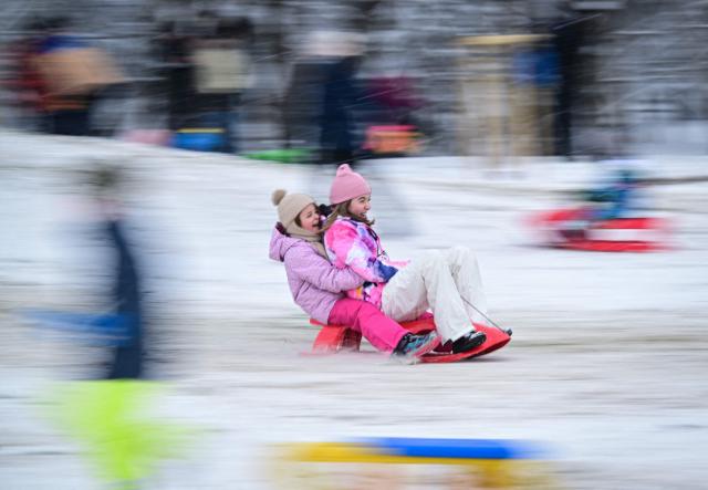Children on a sledge slide down a hill in a snow-covered park in Bucharest, Romania, on January 11, 2025. According to the National Meteorological Administration (ANM), maximum temperatures will generally range between -11 and 0 degrees Celsius, with persistent frost even during the daytime, isolated in the north and central regions, while minimum temperatures will range between -15 and -6 degrees Celsius. Several other regions are under alert for snowfall, frost, and blizzard conditions. (Photo by Daniel MIHAILESCU / AFP)
