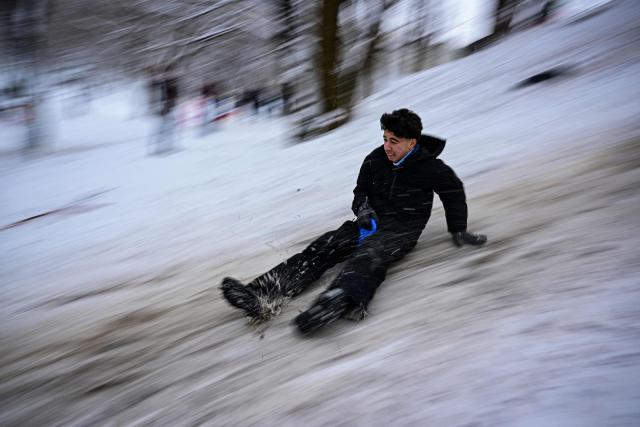 A boy slides down a hill in a snow-covered park in Bucharest, Romania, on January 11, 2025. According to the National Meteorological Administration (ANM), maximum temperatures will generally range between -11 and 0 degrees Celsius, with persistent frost even during the daytime, isolated in the north and central regions, while minimum temperatures will range between -15 and -6 degrees Celsius. Several other regions are under alert for snowfall, frost, and blizzard conditions. (Photo by Daniel MIHAILESCU / AFP)