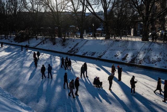 People walk on the ice over the Neukoelln Ship Canal in Berlin's Treptow district in Berlin on January 11, 2026, as the German capital continued to experience sub-zero degrees centigrade. (Photo by John MACDOUGALL / AFP)