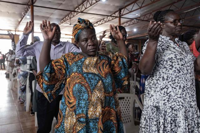 Christian worshippers raise their hands as they praise and pray for a peaceful election at Victory church in Kampala, on January 11, 2026, ahead of the 2026 Ugandan general election. (Photo by Badru Katumba / AFP)