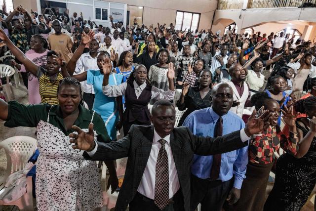 Christian worshippers raise their hands as they praise and pray for a peaceful election at Victory church in Kampala, on January 11, 2026, ahead of the 2026 Ugandan general election. (Photo by Badru Katumba / AFP)
