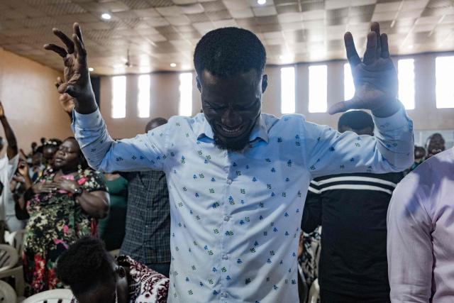 Christian worshippers raise their hands as they praise and pray for a peaceful election at Victory church in Kampala, on January 11, 2026, ahead of the 2026 Ugandan general election. (Photo by Badru Katumba / AFP)