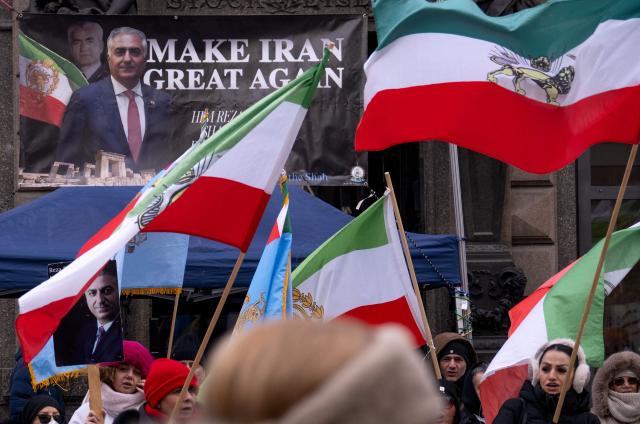 Protesters hold up placards featuring Reza Pahlavi, an Iranian dissident in exile in the United States and son of the last shah of Iran, as wave Pahlavi era Iranian flags during a demonstration against the Iranian government at Stephansplatz square in Vienna, Austria on January 11, 2026. (Photo by Joe Klamar / AFP)