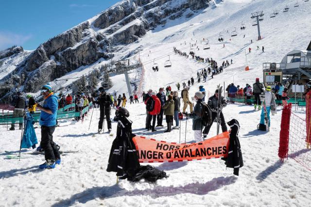 (FILES) Skiers queue for the lift near a sign warning of avalanche risk during the re-opening of the ski resort at Col de la Balme in La Clusaz, French Alps on May 23, 2021 as the country loosened Covid-19 restrictions. Two avalanches killed two skiers in the French Alps on January 11, 2026, resort officials said, following the deaths of three off-piste skiers a day earlier in similar incidents. In one incident, a British skier aged about 50 was buried while skiing off-trail, according to a statement released by La Plagne ski resort in southeastern France. (Photo by Olivier CHASSIGNOLE / AFP)