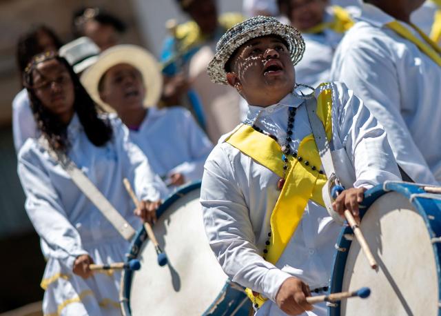 Musicians perform during the traditional Reinado de Nossa Senhora do Rosario, Santa Efigenia e Sao Benedito (Reign of Our Lady of the Rosary, St Efigenia and St. Benedict) festival to honour Chico Rei, through the historic streets of Ouro Preto, Brazil, on January 11, 2026. According to tradition, Chico was the king of a tribe in Congo brought by the Portuguese as a slave and who managed to buy his freedom and that of other slaves to become 'king' in Ouro Preto and, from then on, part of the Brazilian folklore. More than 30 congado guards from Ouro Preto and the region take part in the event. (Photo by Douglas MAGNO / AFP)