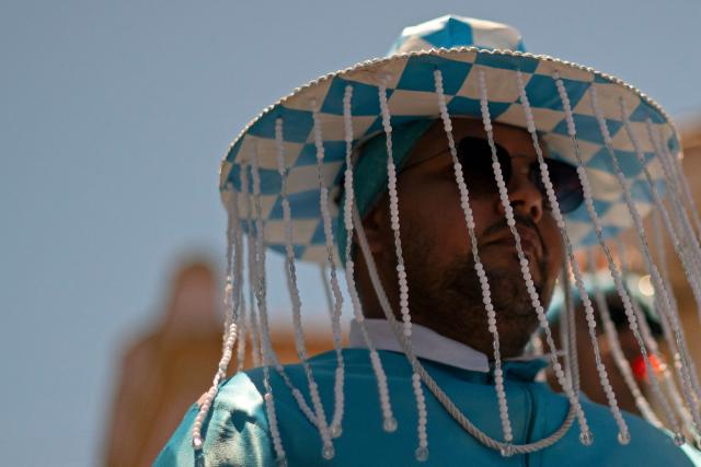 A reveller takes part in the traditional Reinado de Nossa Senhora do Rosario, Santa Efigenia e Sao Benedito (Reign of Our Lady of the Rosary, St Efigenia and St. Benedict) festival to honour Chico Rei, through the historic streets of Ouro Preto, Brazil, on January 11, 2026. According to tradition, Chico was the king of a tribe in Congo brought by the Portuguese as a slave and who managed to buy his freedom and that of other slaves to become 'king' in Ouro Preto and, from then on, part of the Brazilian folklore. More than 30 congado guards from Ouro Preto and the region take part in the event. (Photo by Douglas MAGNO / AFP)