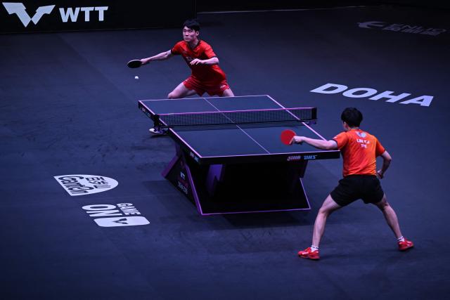 South Korea's Jang Woojin (top) hits a return against Taiwan's Lin Yun-ju during their men's singles final match in the World Table Tennis (WTT) Champions tournament at the Infinity Arena in Doha on January 11, 2026. (Photo by Mahmud HAMS / AFP)