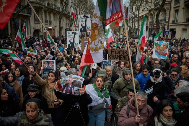 Protestors shout slogans and wave flags of Iran from before the 1979 revolution, with the lion and sun emblems, during a demonstration to support mass rallies denouncing the Islamic republic in Iran in Paris on January 11, 2026. At least 192 protesters have been killed in Iran's biggest movement against the Islamic republic in more than three years, as warnings grew that authorities were committing a "massacre" to quell the demonstrations. The protests, initially sparked by anger over the rising cost of living, have now become a movement against the theocratic system in place in Iran since the 1979 revolution and have already lasted two weeks. (Photo by Kiran RIDLEY / AFP)