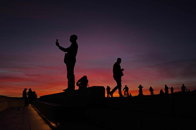 TOPSHOT - People look at the sunset on the French riviera city of Nice, southeastern France on January 11, 2026. (Photo by Valery HACHE / AFP)