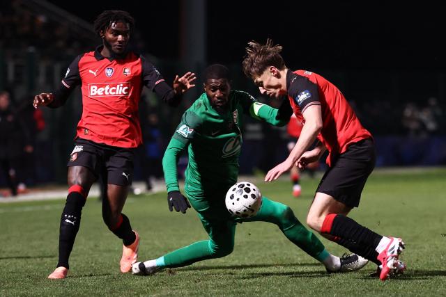 Rennes' French defender Anthony Rouault (R) fights fort the ball with Chantilly Dramane Kone (L) during the French Cup round of 32 football match between US Chantilly and Stade Rennais at the Pierre-Brisson stadium in Beauvais, northern France on January 11, 2026. (Photo by Anne-Christine POUJOULAT / AFP)