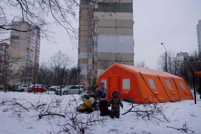 Children play with a Christmas tree by a tent of Point of Invincibility in Kyiv on January 11, 2026, where people can charge devices and warm themself, following Russian missile and drone attacks on Ukrainian energy infrastructure amid the Russian invasion in Ukraine. (Photo by Tetiana DZHAFAROVA / AFP)