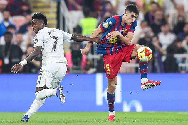 Real Madrid's Brazilian forward #07 Vinicius Junior (L) and Barcelona's Spanish defender #05 Pau Cubarsi fight for the ball during the Spanish Super Cup final football match between FC Barcelona and Real Madrid at the King Abdullah Stadium in Jeddah on January 11, 2026. (Photo by Haitham AL-SHUKAIRI / AFP)