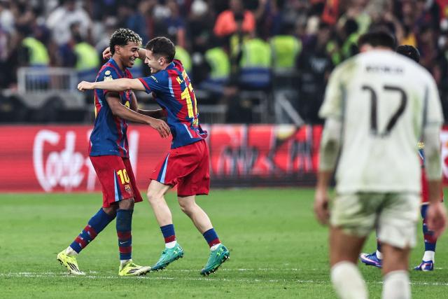 Barcelona's Spanish forward #10 Lamine Yamal and Barcelona's Spanish midfielder #17 Marc Casado celebrate after winning the Spanish Super Cup final football match between FC Barcelona and Real Madrid at the King Abdullah Stadium in Jeddah on January 11, 2026. (Photo by Fadel SENNA / AFP)
