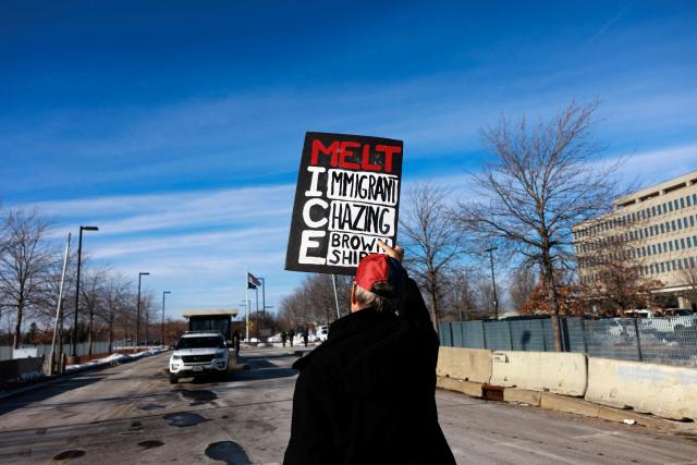 A protester holds a sign reading “Melt ICE” outside the Whipple Building, an ICE facility, shortly before being detained by federal agents in Minneapolis, Minnesota, on January 11, 2026. A US Immigration and Customs Enforcement (ICE) agent shot and killed 37-year-old Renee Nicole Good on the streets of Minneapolis on January 7, leading to huge protests and outrage from local leaders who rejected White House claims she was a domestic terrorist. (Photo by Kerem YUCEL / AFP)
