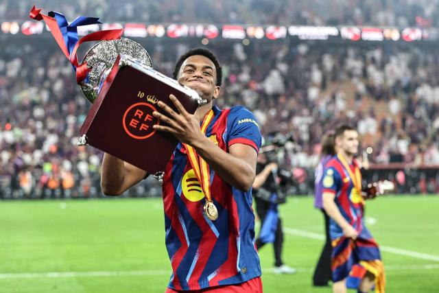 Barcelona's Spanish defender #03 Alex Balde celebrates with the trophy after winning the Spanish Super Cup final football match between FC Barcelona and Real Madrid at the King Abdullah Stadium in Jeddah on January 11, 2026. (Photo by Haitham AL-SHUKAIRI / AFP)
