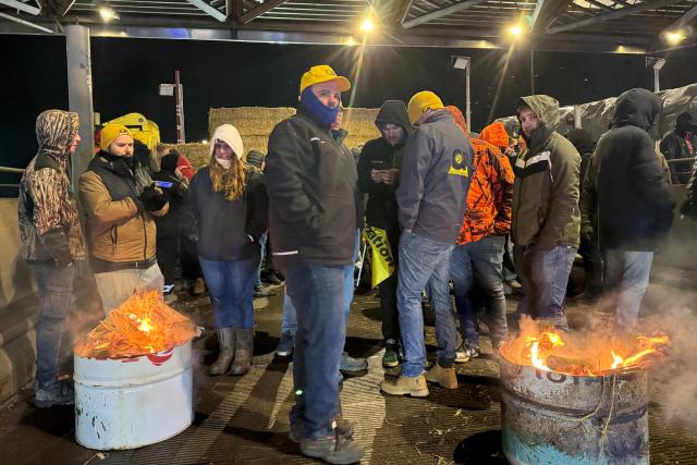 French farmers get warm as they set up a blockade called by the agricultural union Coordination Rurale (CR), as part of national protests against the EU-Mercosur agreement at the A1 highway toll in Fresnes-les-Montauban, northern France on January 11, 2026 (Photo by Benjamin BOULY RAMES / AFP)