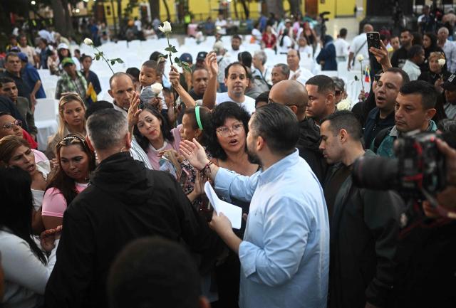 Deputy Nicolas Maduro Guerra, son of ousted President Nicolas Maduro, speaks with Evangelical faithfuls as he leaves a rally in support of his father and Cilia Flores at Plaza Bolivar in Caracas on January 11, 2026.  (Photo by Federico PARRA / AFP)