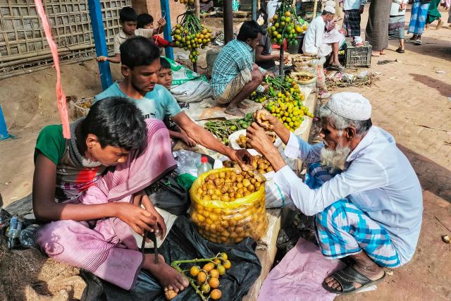 Rohingya refugees shop betel nuts at a market in the Kutupalong refugee camp of Ukhia on January 11, 2026. In Bangladesh's sprawling Rohingya camps of Cox's Bazar, where more than a million refugees forced to flee Myanmar live in squalid conditions, hope is a fragile but persistent force. In rows of bamboo shelters and muddy lanes, refugees who escaped Myanmar nearly a decade ago await developments more than 8,000 kilometres (5,000 miles) away at the International Court of Justice (ICJ) in The Hague, where a genocide case against Myanmar opens on January 12. (Photo by MH Mustafa / AFP) / TO GO WITH 'Bangladesh-Myanmar-Gambia-ICJ-Rohingya-Genocide' REPORTAGE
