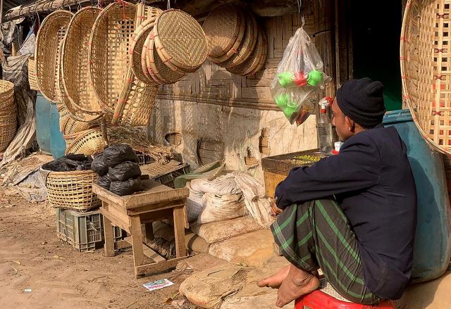 A Rohingya refugee sits outside a shop selling bamboo items at the Kutupalong refugee camp in Ukhia on January 11, 2026. In Bangladesh's sprawling Rohingya camps of Cox's Bazar, where more than a million refugees forced to flee Myanmar live in squalid conditions, hope is a fragile but persistent force. In rows of bamboo shelters and muddy lanes, refugees who escaped Myanmar nearly a decade ago await developments more than 8,000 kilometres (5,000 miles) away at the International Court of Justice (ICJ) in The Hague, where a genocide case against Myanmar opens on January 12. (Photo by MH Mustafa / AFP) / TO GO WITH 'Bangladesh-Myanmar-Gambia-ICJ-Rohingya-Genocide' REPORTAGE