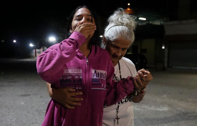 Lorealbert Gutierrez, (L) 19, is comforted while waiting for news on the release of prisoners, outside El Rodeo I prison in Guatire, Miranda State, some 30 kilometers east of Caracas on January 11, 2026. Venezuelans were waiting for more political prisoners to be released, as ousted president Nicolas Maduro defiantly claimed from his US jail cell that he is "doing fine" after being seized by US forces a week ago. (Photo by Pedro MATTEY / AFP)