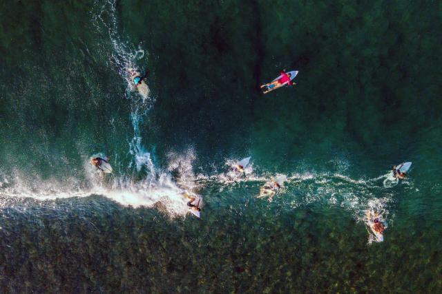 An aerial view shows surfers riding a wave in Lhoknga beach, Indonesia's Aceh province on January 12, 2026. (Photo by CHAIDEER MAHYUDDIN / AFP)
