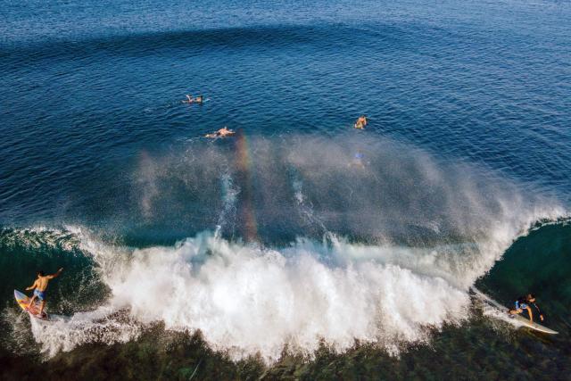 TOPSHOT - An aerial view shows surfers riding a wave in Lhoknga beach, Indonesia's Aceh province on January 12, 2026. (Photo by CHAIDEER MAHYUDDIN / AFP)