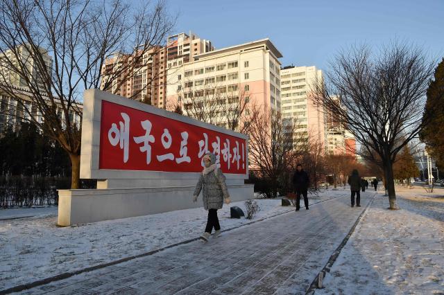 People walk along a snow-covered sidewalk in Pyongyang on January 12, 2026. (Photo by KIM Won Jin / AFP)