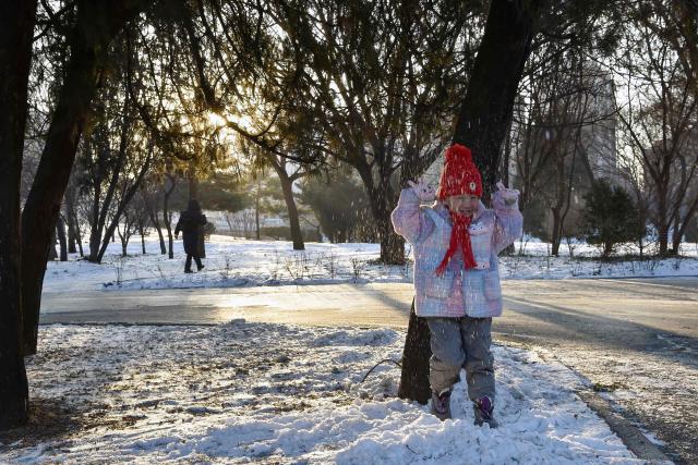A child plays with snow in Pyongyang on January 12, 2026. (Photo by KIM Won Jin / AFP)