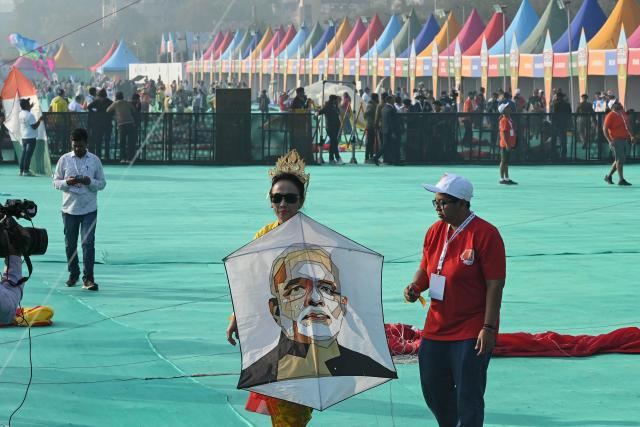 A tourist prepares to fly a kite featuring India's Prime Minister Narendra Modi before his arrival with German Chancellor Friedrich Merz during the International Kite Festival in Ahmedabad on January 12, 2026. (Photo by Shammi MEHRA / AFP)