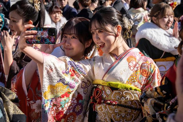 Women dressed in kimonos pose for a photo as they arrive to attend a ceremony at Todoroki Arena to mark "Coming of Age Day" to honour people who turn 20 this year to signify adulthood, in Kawasaki, Kanagawa prefecture on January 12, 2026. (Photo by Yuichi YAMAZAKI / AFP)