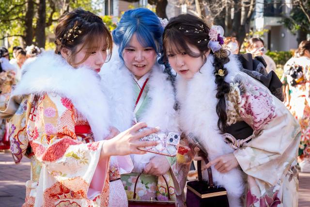 Women dressed in kimonos pose for a photo as they arrive to attend a ceremony at Todoroki Arena to mark "Coming of Age Day" to honour people who turn 20 this year to signify adulthood, in Kawasaki, Kanagawa prefecture on January 12, 2026. (Photo by Yuichi YAMAZAKI / AFP)