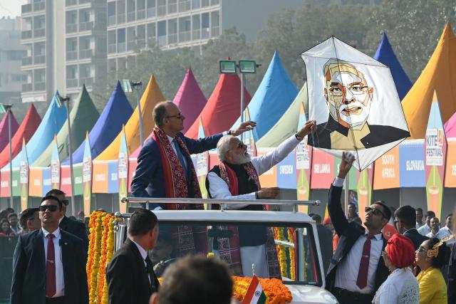 TOPSHOT - India's Prime Minister Narendra Modi (centre R) flies a kite with his portrait alongside German Chancellor Friedrich Merz during the International Kite Festival in Ahmedabad on January 12, 2026. (Photo by Shammi MEHRA / AFP)