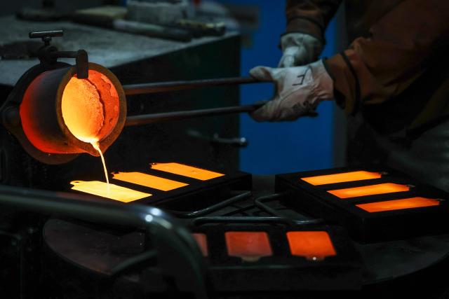 (FILES) A refiner pours liquid gold from a furnace into casts at the ABC Refinery smelter in Sydney on April 29, 2025. Gold and silver surged to record highs after the US Justice Department targeted the Federal Reserve in an investigation, fuelling fears over the bank's independence and raising demand for safe haven assets. (Photo by DAVID GRAY / AFP)