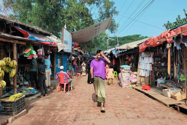 A Rohingya refugee walks across a market at the Kutupalong refugee camp in Ukhia on January 12, 2026. In Bangladesh's sprawling Rohingya camps of Cox's Bazar, where more than a million refugees forced to flee Myanmar live in squalid conditions, hope is a fragile but persistent force. In rows of bamboo shelters and muddy lanes, refugees who escaped Myanmar nearly a decade ago await developments more than 8,000 kilometres (5,000 miles) away at the International Court of Justice (ICJ) in The Hague, where a genocide case against Myanmar opens on January 12. (Photo by MH Mustafa / AFP)