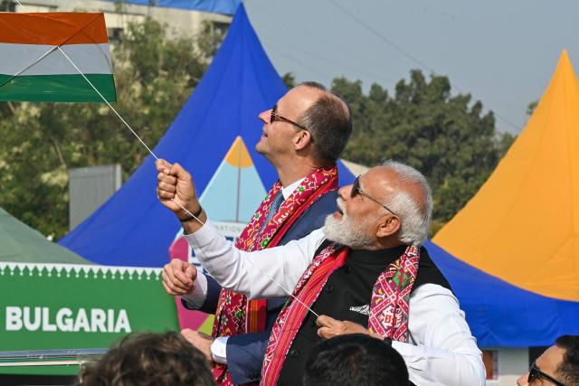India's Prime Minister Narendra Modi (R) flies a kite alongside German Chancellor Friedrich Merz during the International Kite Festival in Ahmedabad on January 12, 2026. (Photo by Shammi MEHRA / AFP)