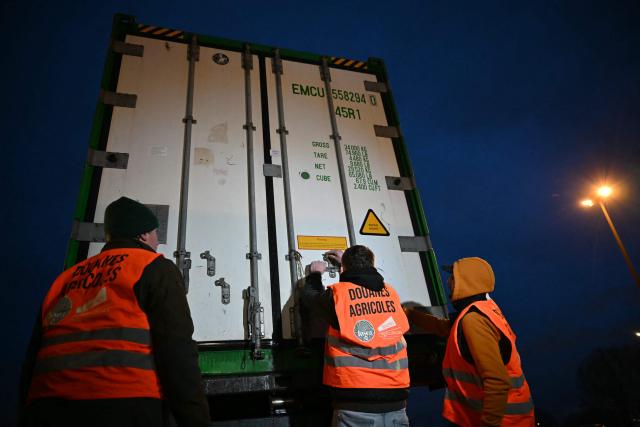 French farmers open a truck to inspect transport of foreign products, as part of national protests against the EU-Mercosur agreement and the government's handling of the contagious nodular dermatitis (CND) epidemic, on the harbour of Le Havre, northwestern France on January 12, 2026. (Photo by Lou BENOIST / AFP)