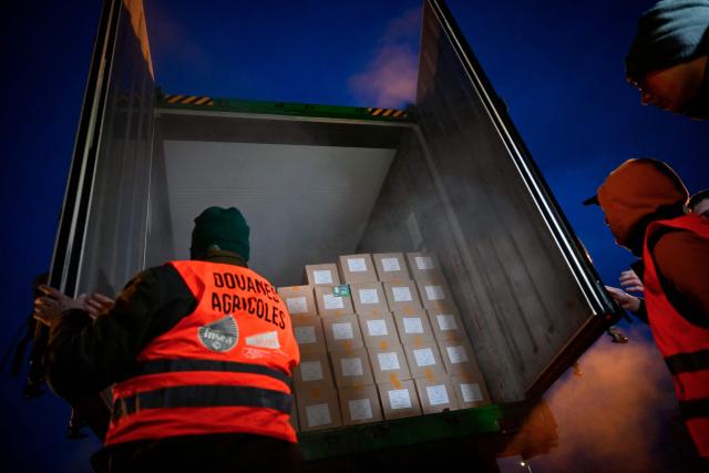 A French farmer, wearing a fake safety vest of Customs, opens a truck to inspect transport of foreign products, as part of national protests against the EU-Mercosur agreement and the government's handling of the contagious nodular dermatitis (CND) epidemic, on the harbour of Le Havre, northwestern France on January 12, 2026. (Photo by Lou BENOIST / AFP)